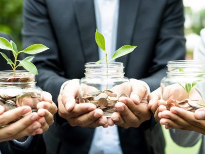 Business people holding glass jars with plants growing from money